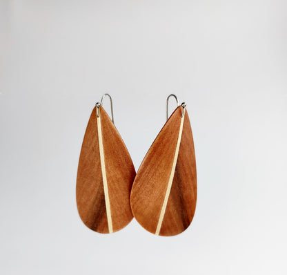 A pair of teardrop-shaped wooden dangle earrings inspired from a feather with a natural wood grain pattern and a thin light-colored center stripe, suspended from simple metal hooks against a plain light gray background.