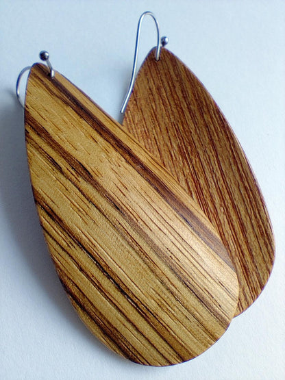 Wooden teardrop earrings with a natural striped wood grain pattern and silver-tone wire hooks, shown on a plain light background.