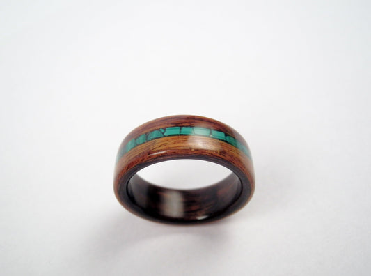 A rosewood wooden ring band with a polished dark brown finish and a central inlay of malachite stones, shown on a plain light background.