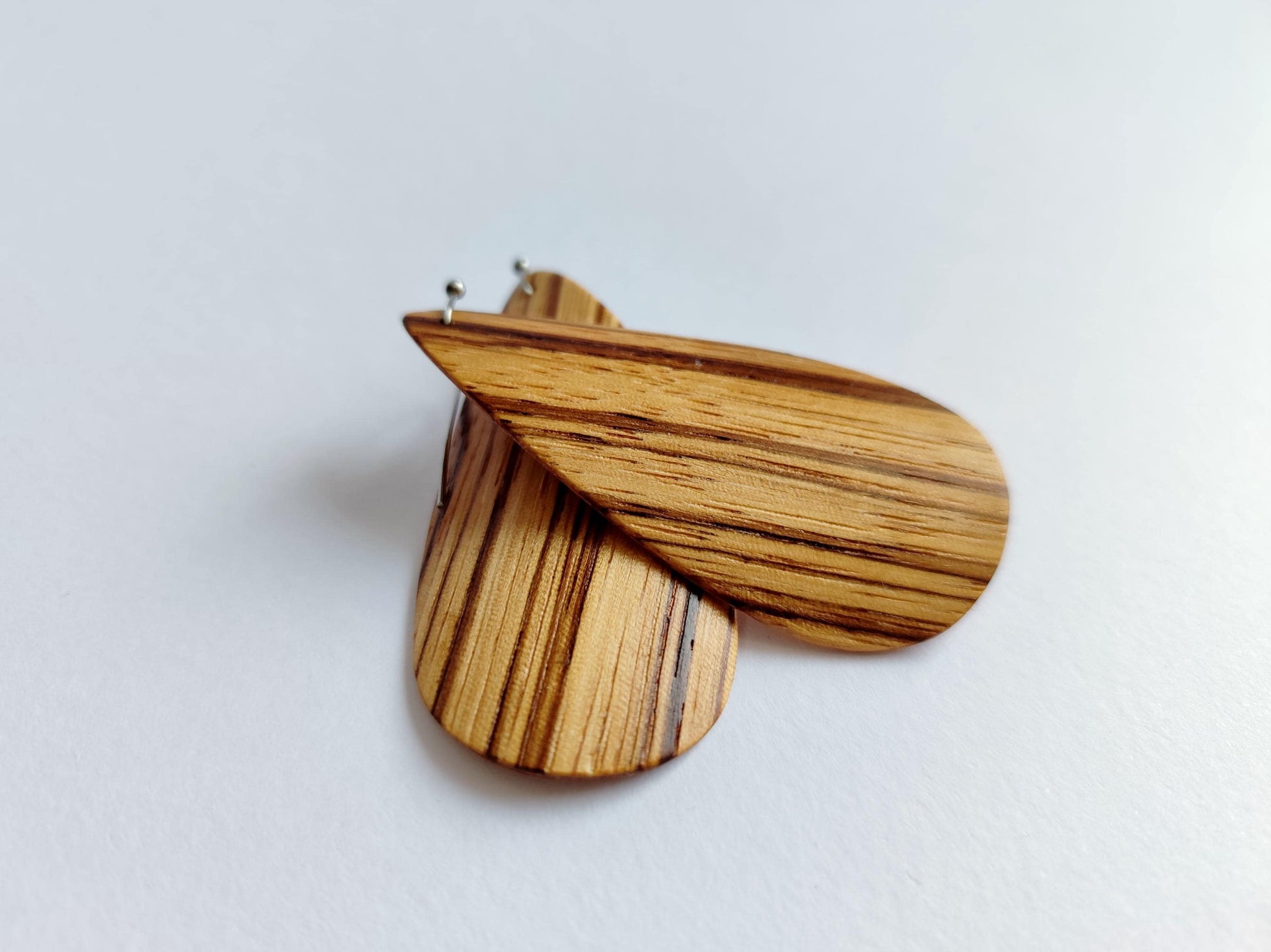 A pair of wooden dangle earrings with a natural striped grain pattern, shown on a plain light gray background.