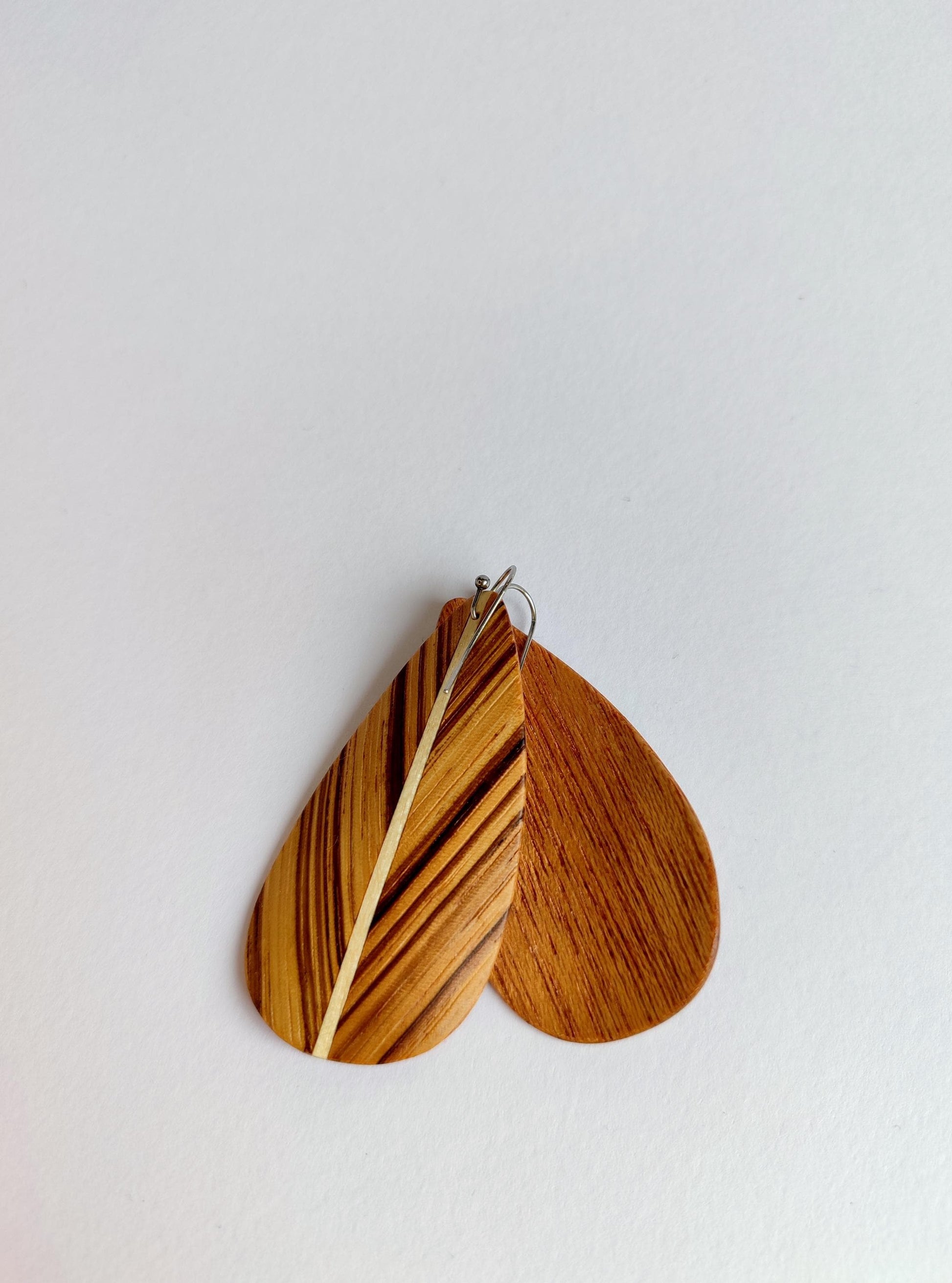 Two teardrop-shaped wooden earrings with natural wood grain patterns, displayed against a plain white background.