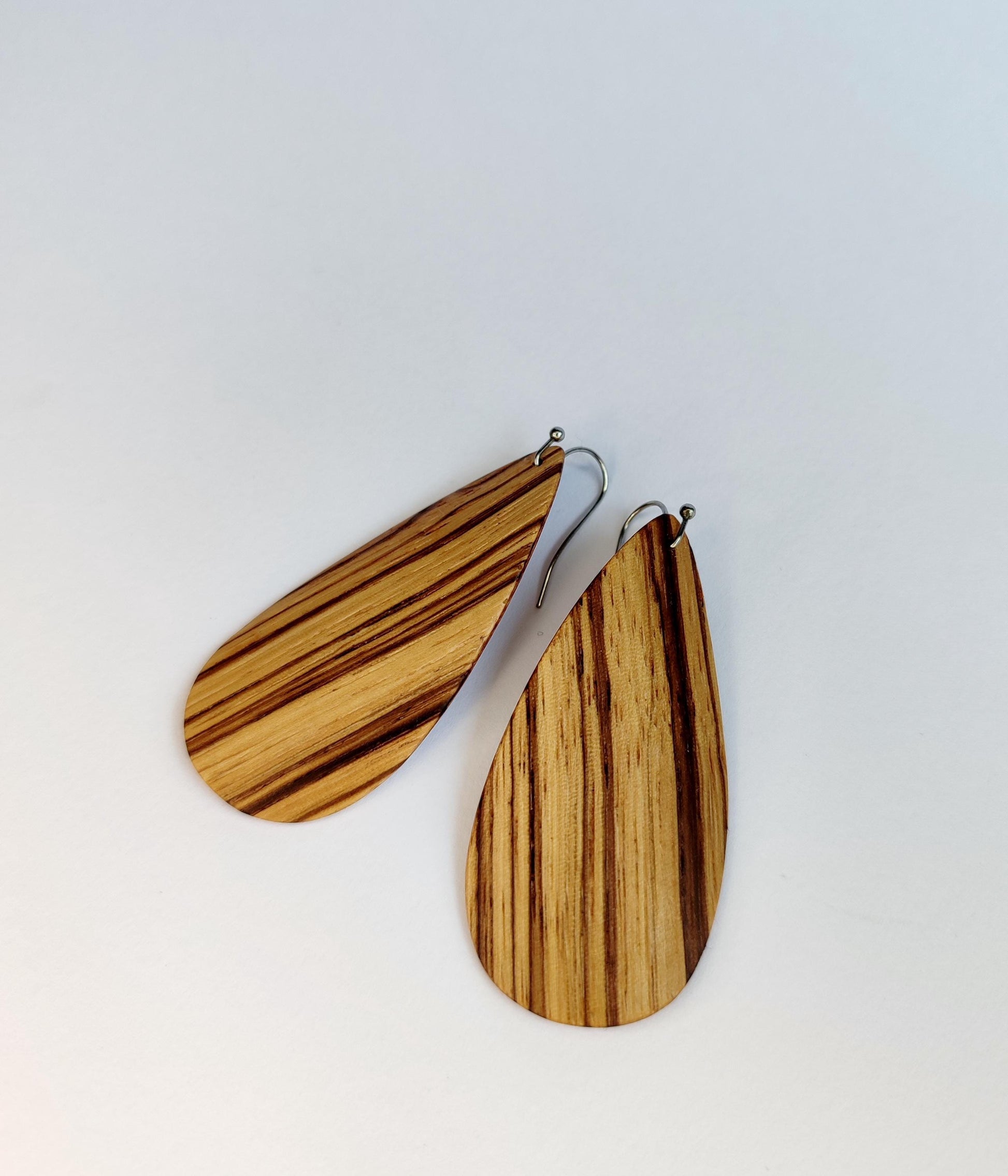 Tear-drop wooden dangle earrings with a natural striped wood grain pattern, shown on a plain light background.