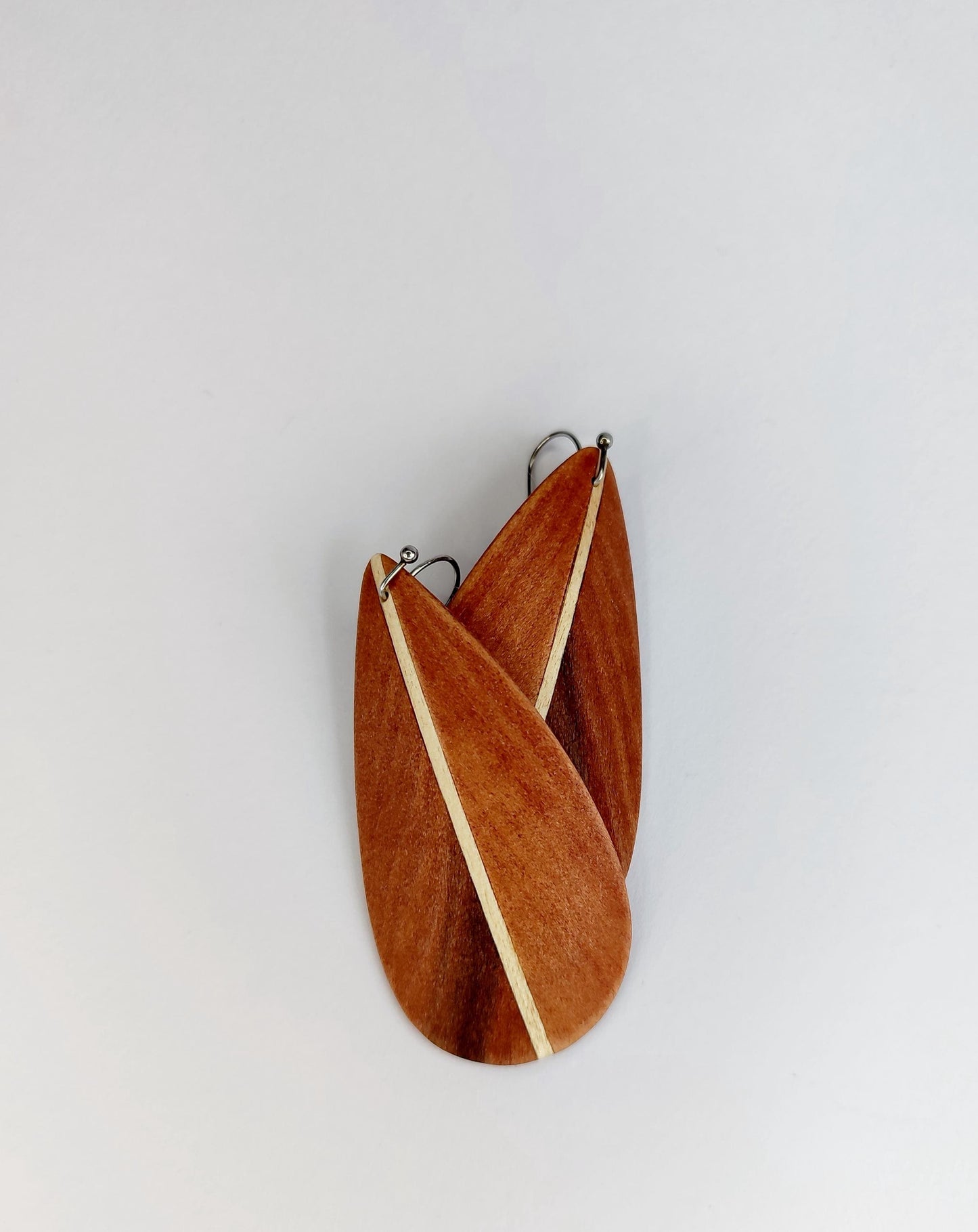 A pair of wooden wall art panels shaped like stylized leaves or teardrops, with a natural wood grain pattern and small metal hanging loops at the top, shown against a plain light gray background.
